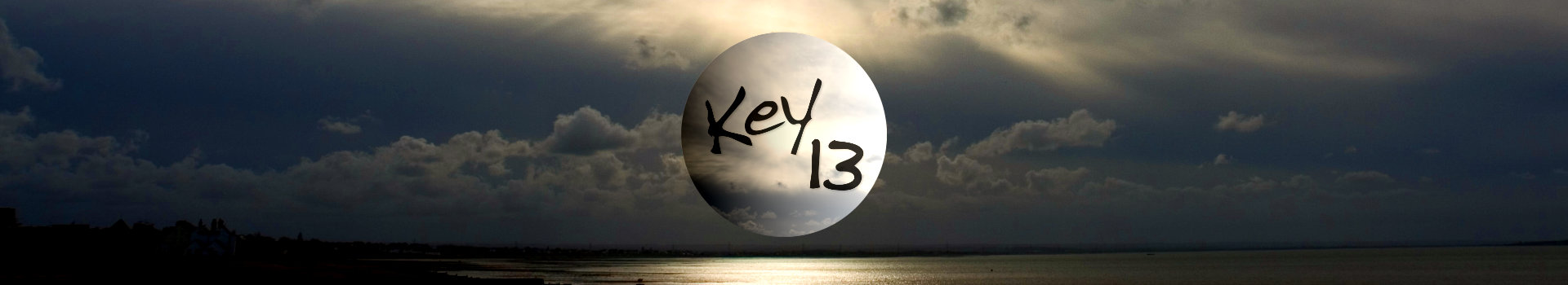 Current Key 13 website banner photo as of 2025 - a narrowly cropped horizontal picture of a sunset over the sea, with dark clouds in the sky and the sun glinting off the water. In the middle, a floating pale cream cloudy globe with the Key 13 logo written in black in a graffiti-like font.