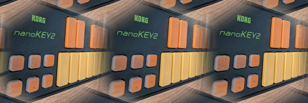 A black miniature midi keyboard, with yellow and orange keys, orange buttons and green writing. The photo has been processed with a stupid effect to repeat it like a kaleidoscope
